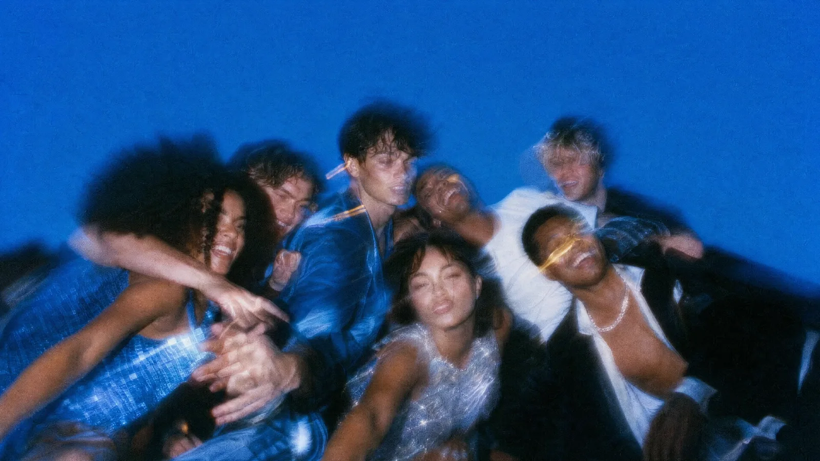 A group of friends outside at night, the sky dark above them.
